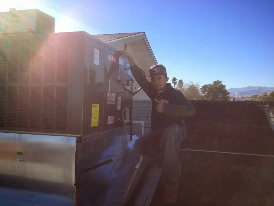 HVAC technician performing AC Tune-Up on a rooftop unit in University Heights